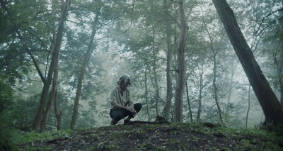 a person sitting on a hill in the woods