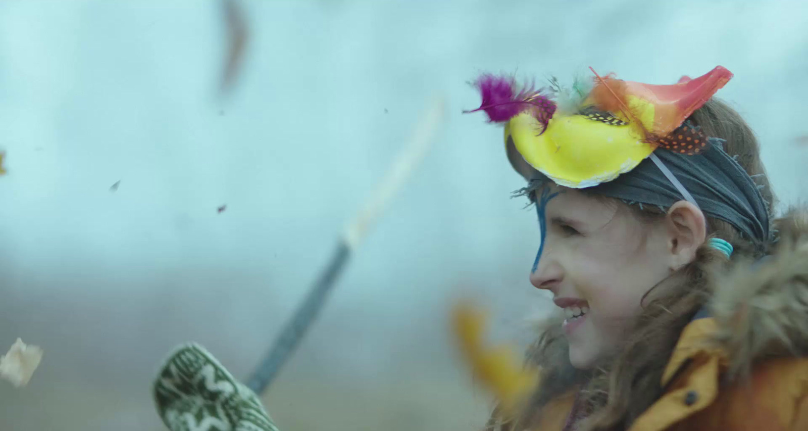 a young girl wearing a feathered hat and holding a cell phone