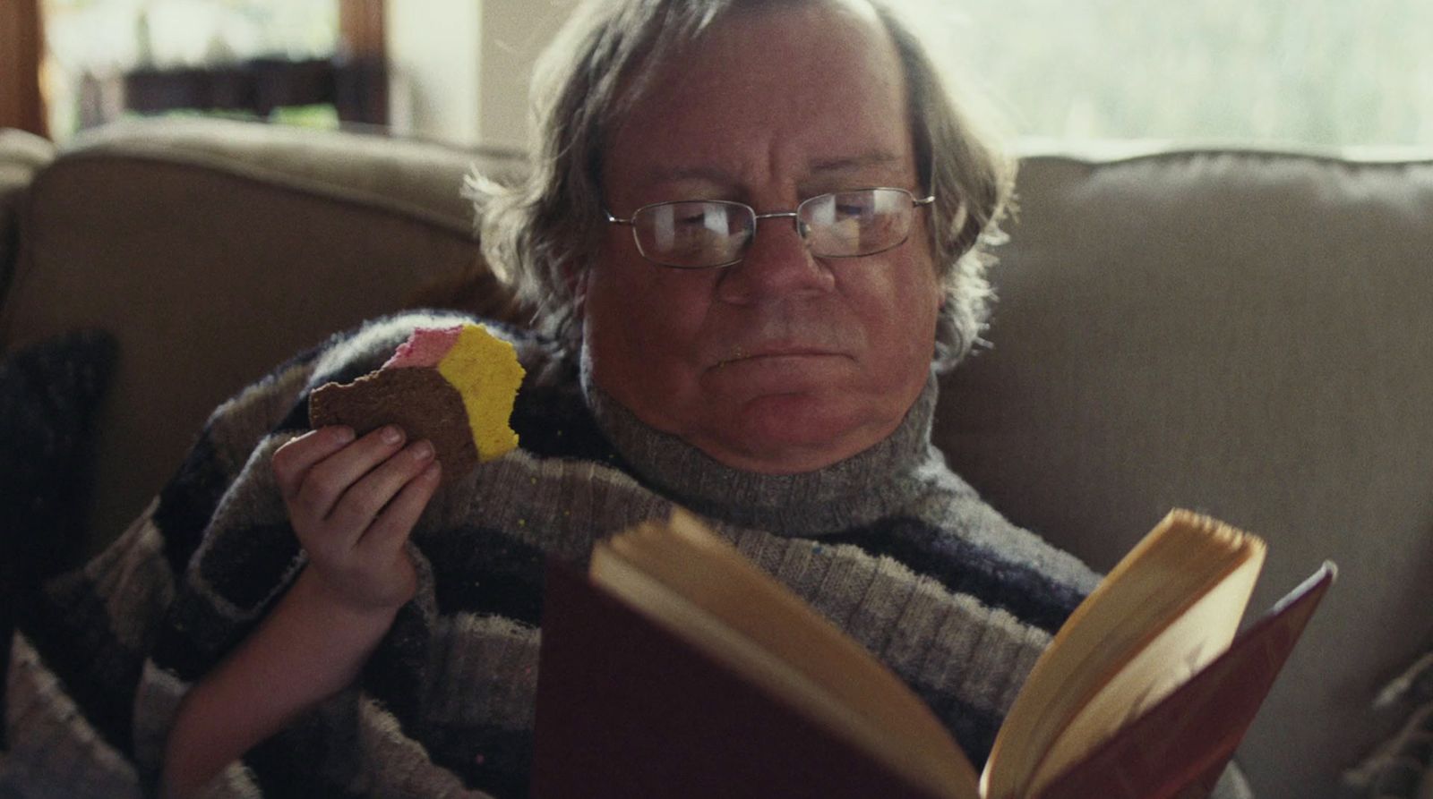 a man sitting on a couch reading a book