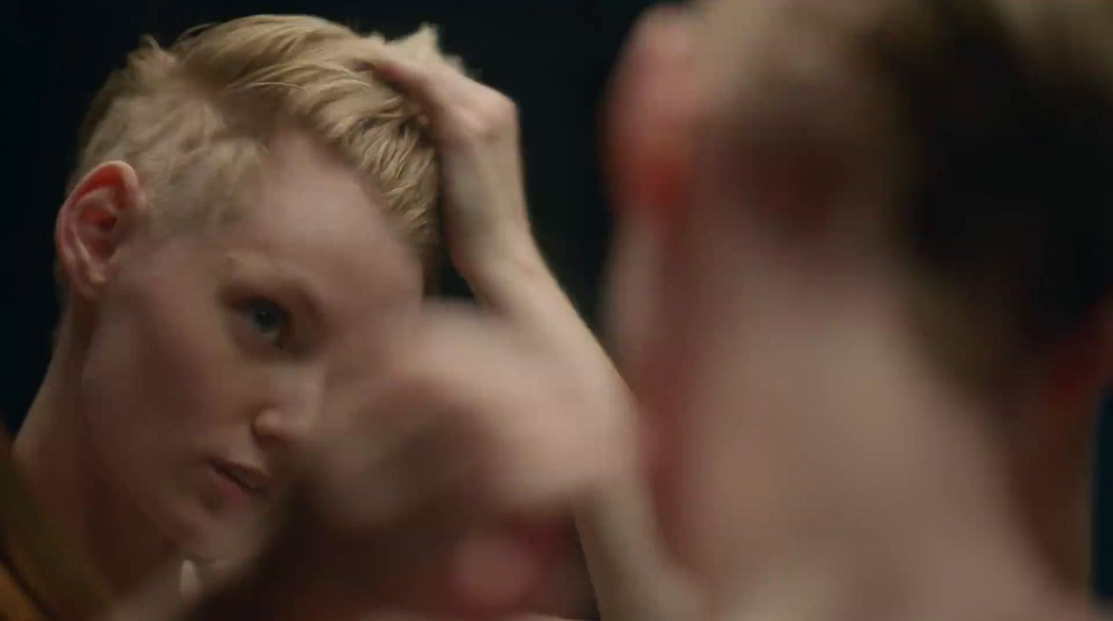 a man is brushing his hair in front of a mirror