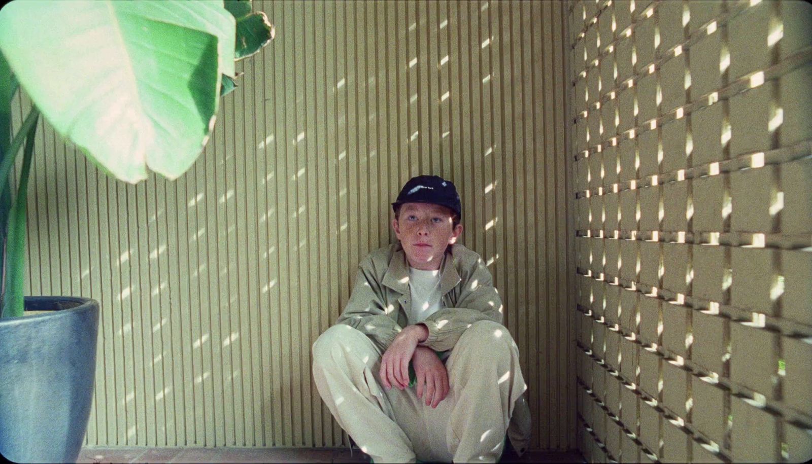 a man sitting on the ground next to a plant