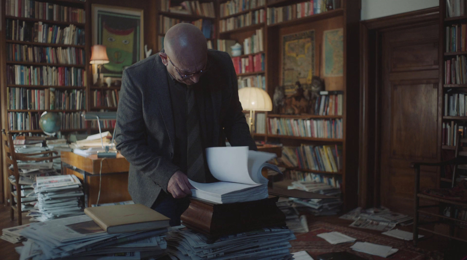 a man standing over a pile of books in a library