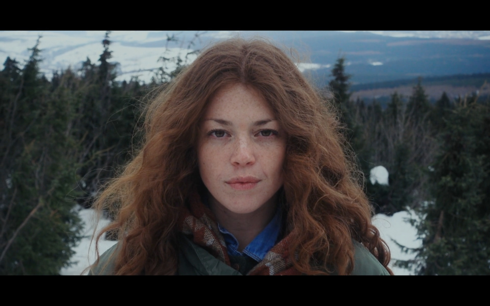 a woman with long red hair standing in the snow