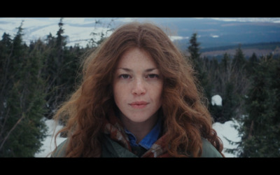 a woman with long red hair standing in the snow