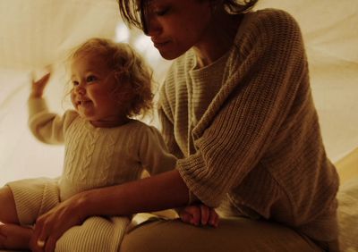 a woman sitting next to a little girl on a bed