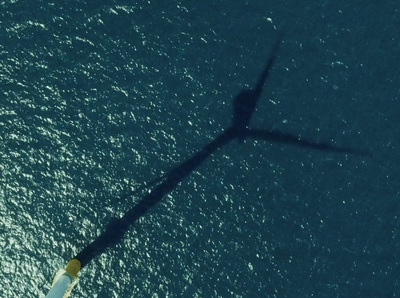 a long shadow of a boat on the water