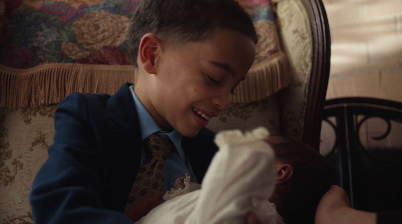 a young boy holding a baby in a chair