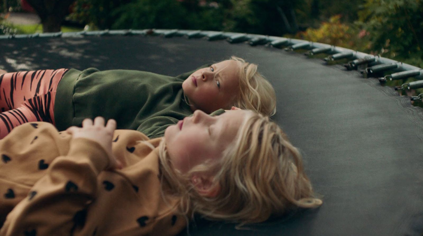 two children laying on a trampoline in a park