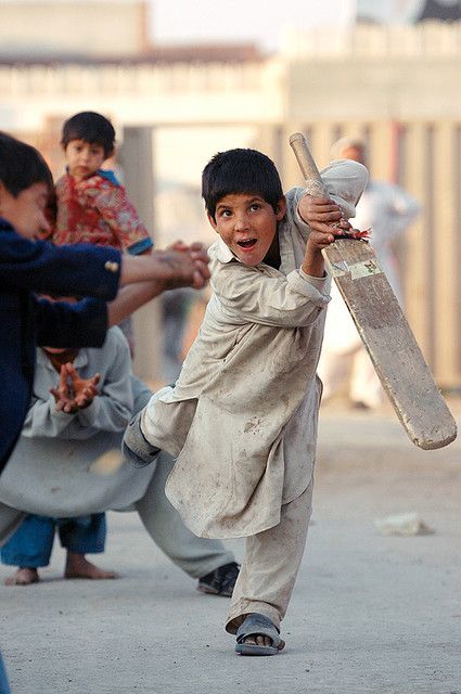 a young boy holding a baseball bat on a street