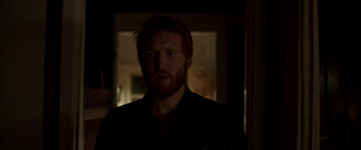 a man with a beard standing in a dark room