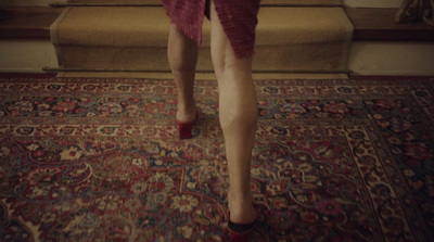 a woman in high heels walking down a carpeted hallway