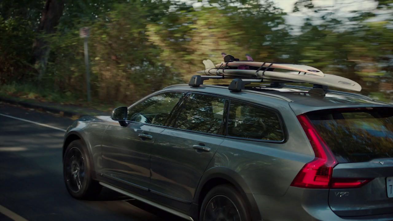 a car driving down a road with a surfboard on top of it