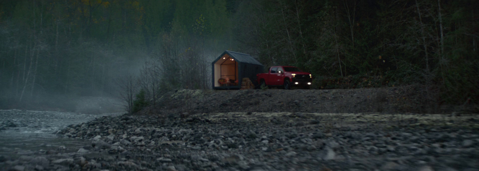 a red truck parked next to a river