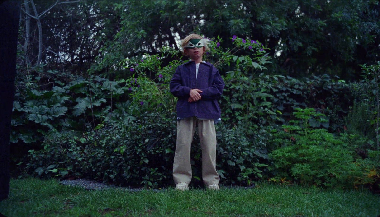 a man standing in the grass wearing a mask