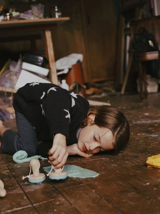 a young girl laying on the floor with a pair of shoes