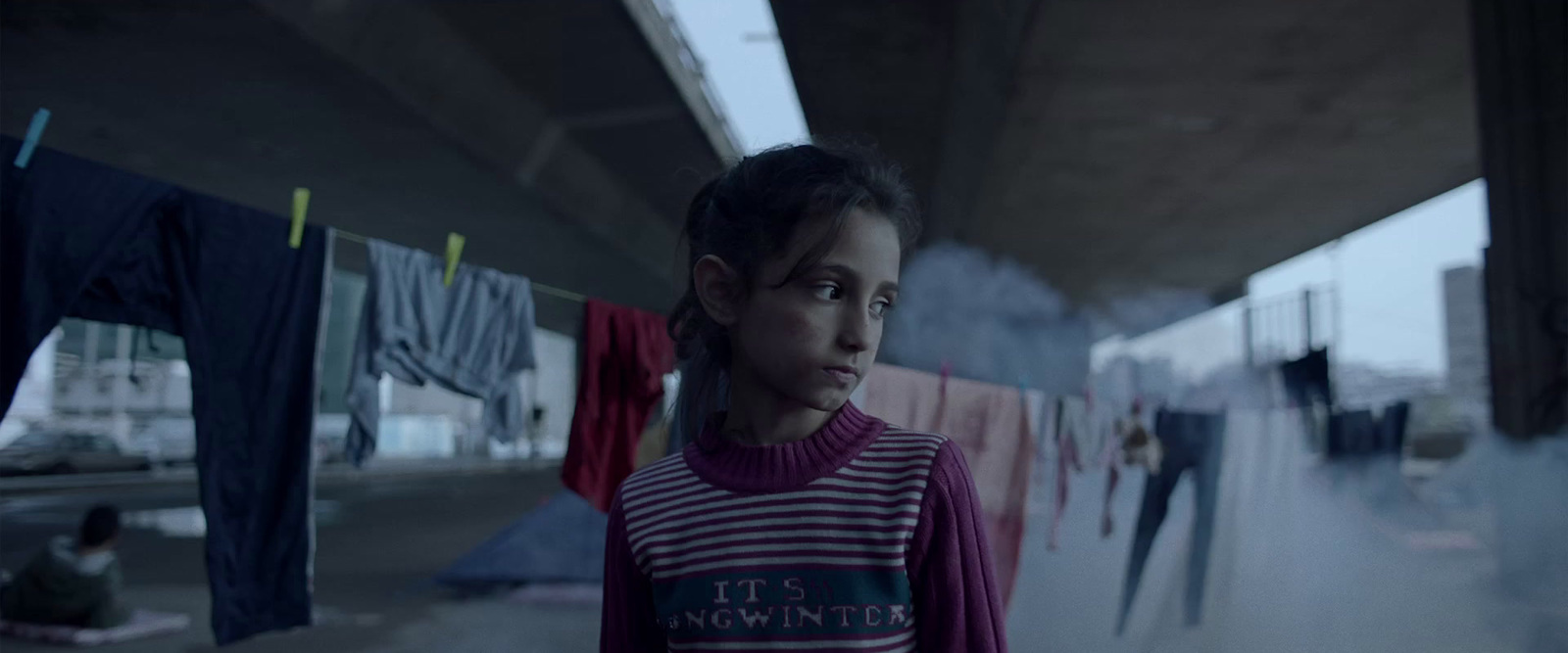 a young girl standing in front of clothes hanging on a line