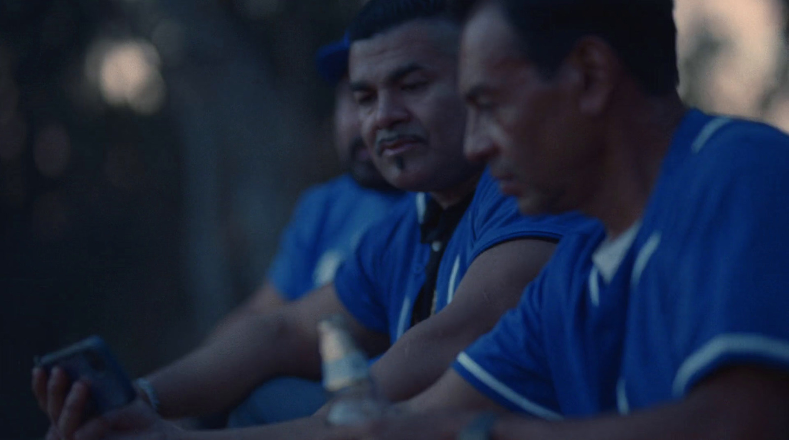 two men sitting next to each other looking at a cell phone