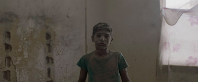 a young boy standing in a dirty room