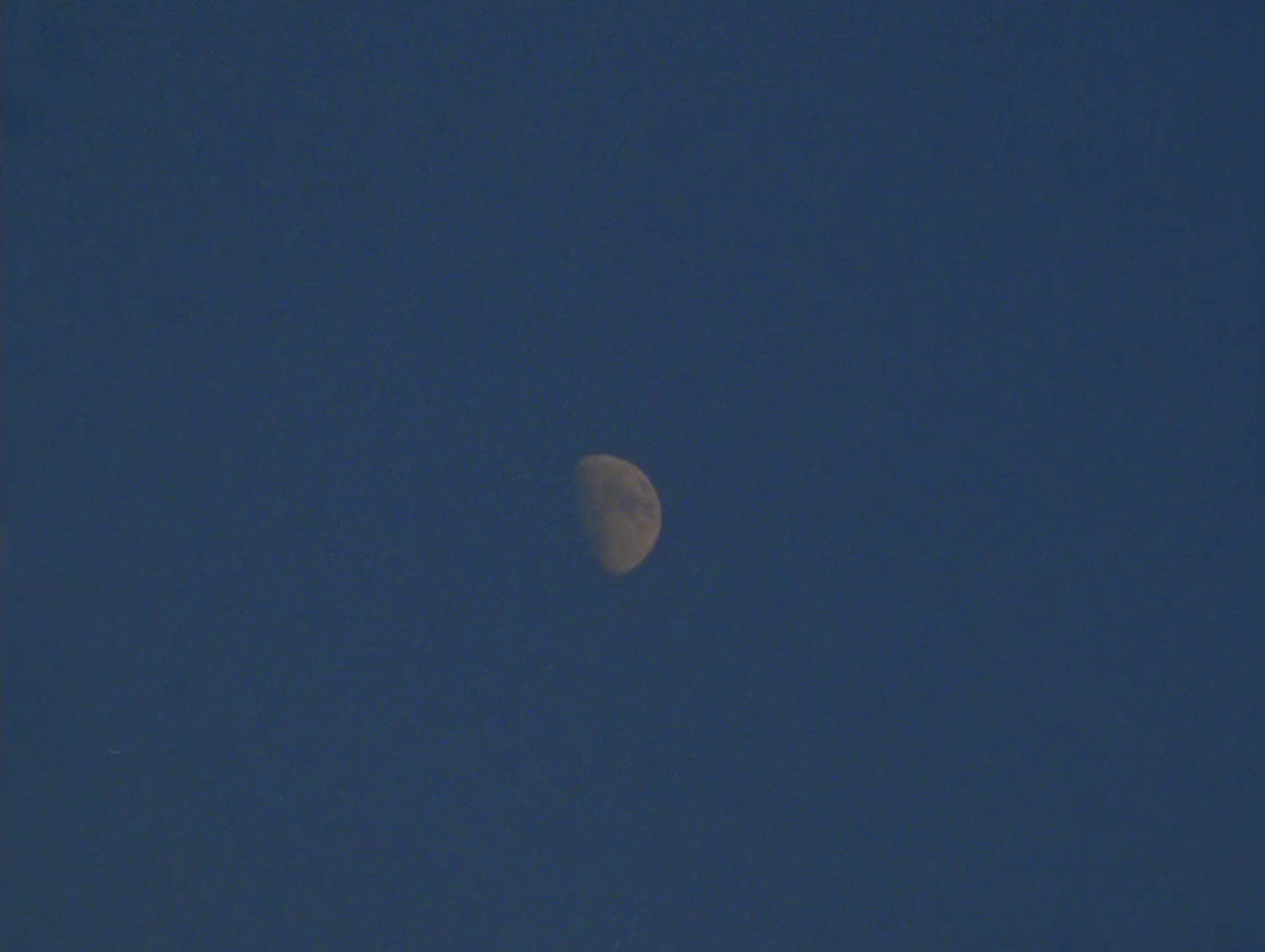 a half moon in a clear blue sky