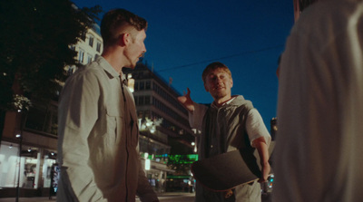 two men standing on the side of a road talking