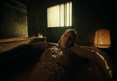 a woman laying in a bathtub covered in mud