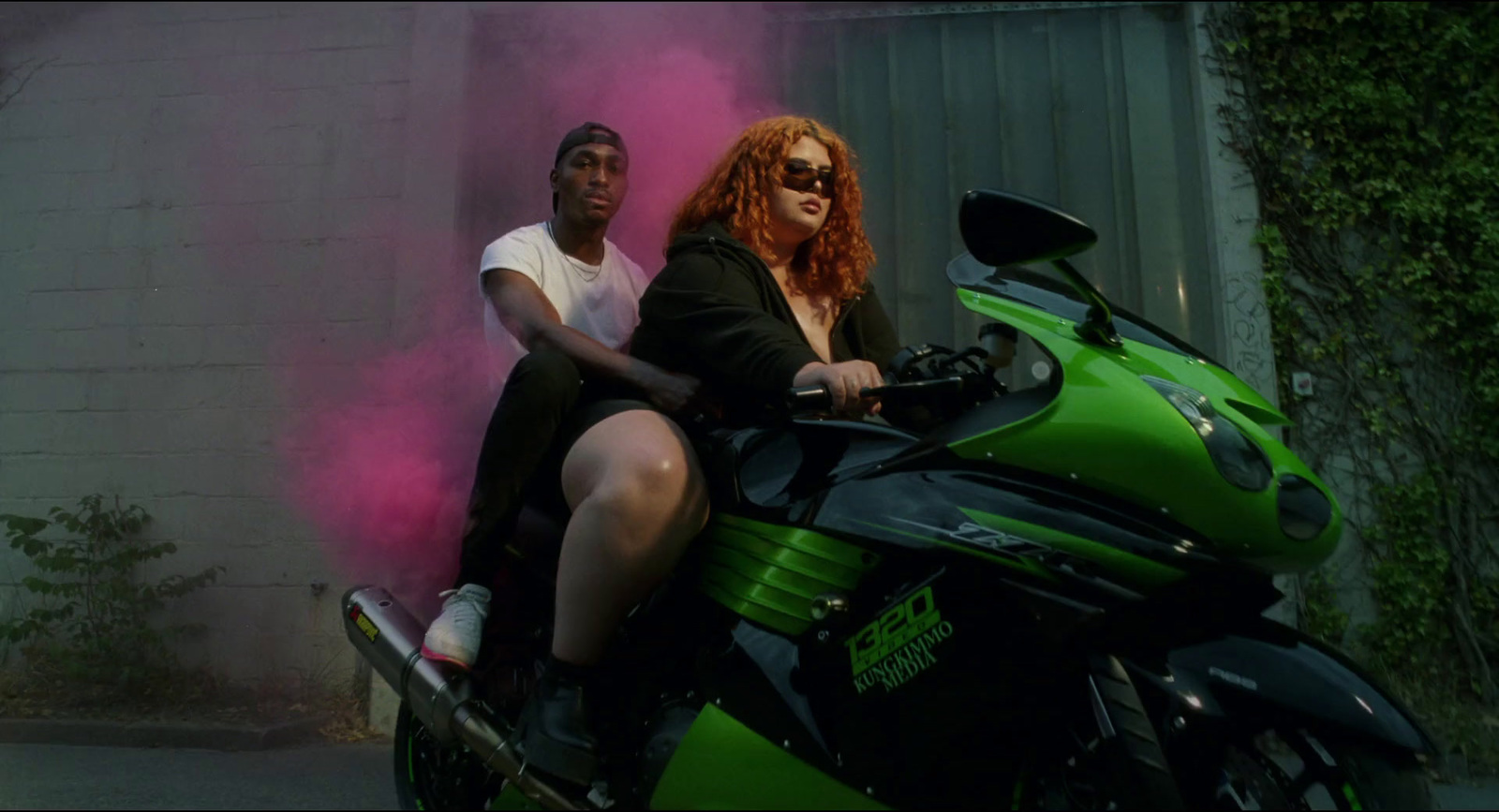 a man and a woman sitting on a green motorcycle