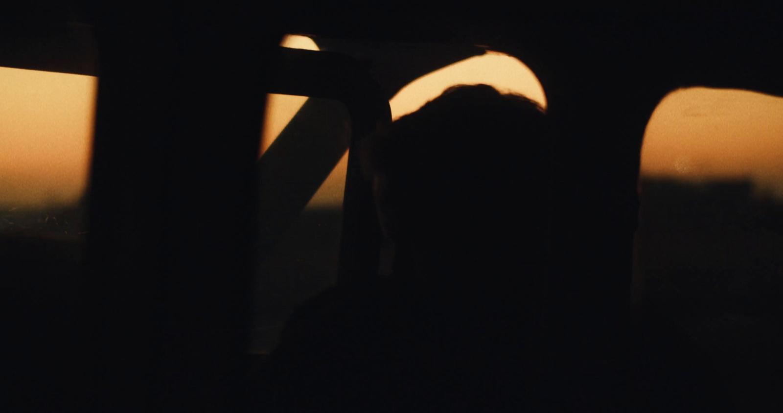 a silhouette of a person looking out a window at the sunset