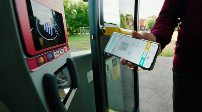 a person holding a cell phone and entering a bus