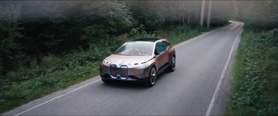 a car driving down a road next to a forest