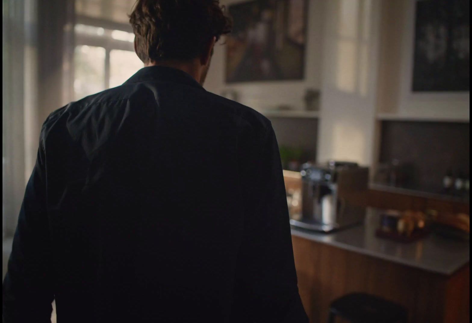 a man standing in a kitchen looking out the window