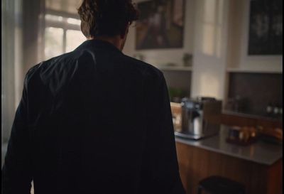 a man standing in a kitchen looking out the window