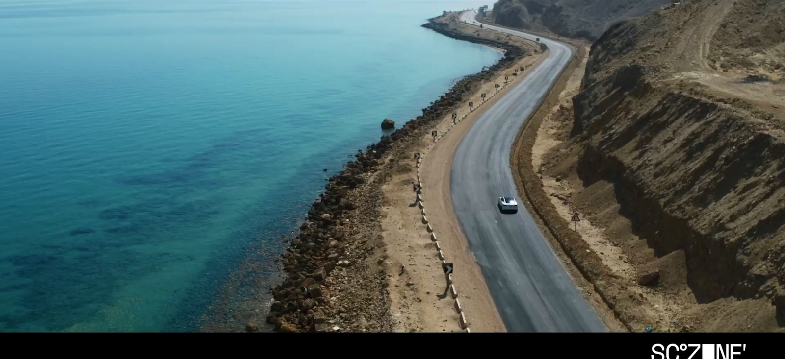 a car driving down a road next to the ocean