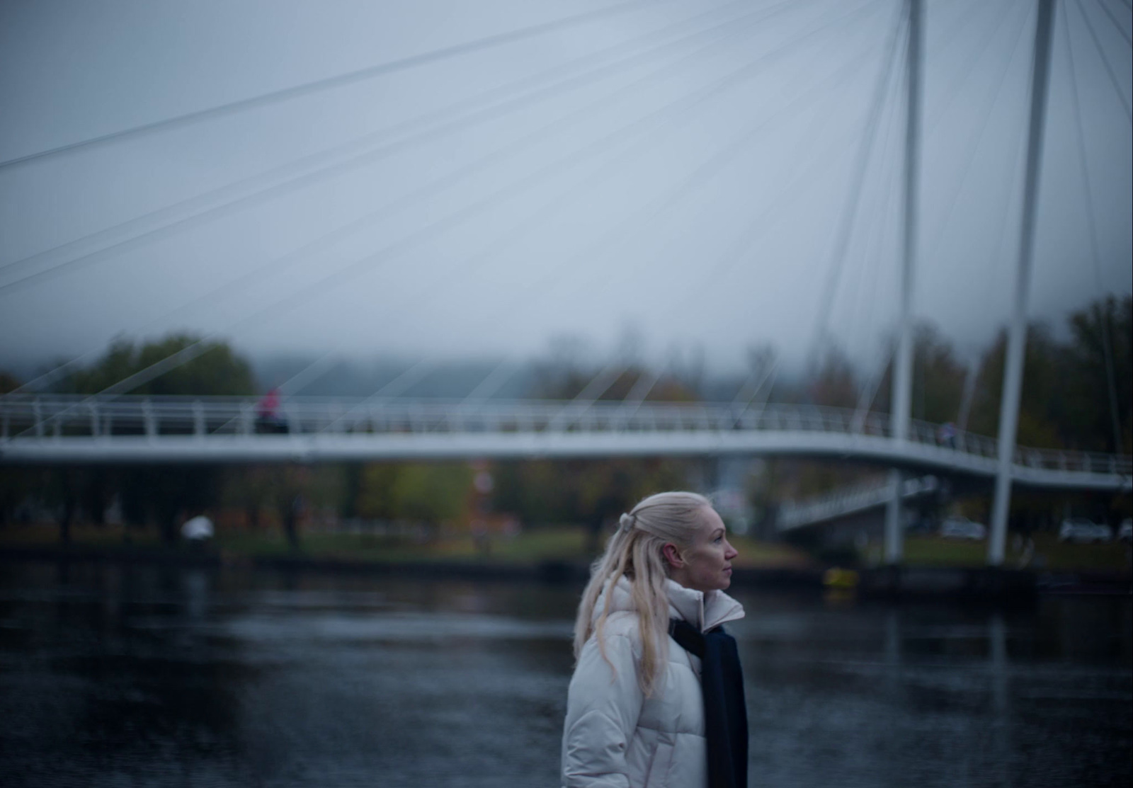 a woman in a white jacket standing on a bridge