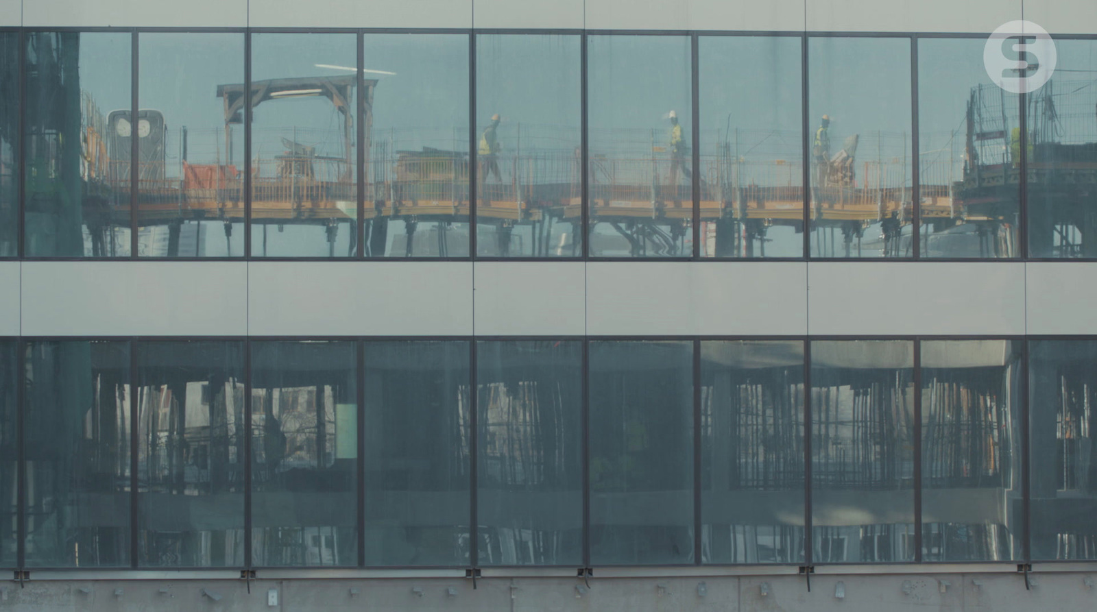 the reflection of a crane in the windows of a building