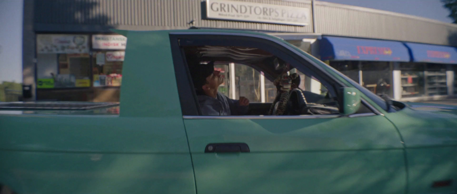 a man sitting in the driver's seat of a green truck