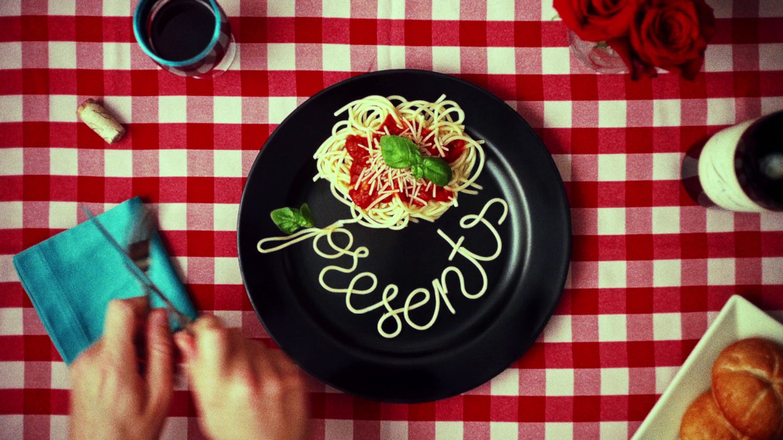 a plate of spaghetti with sauce and basil on a red and white checkered table