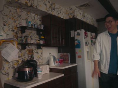 a man standing in a kitchen next to a refrigerator