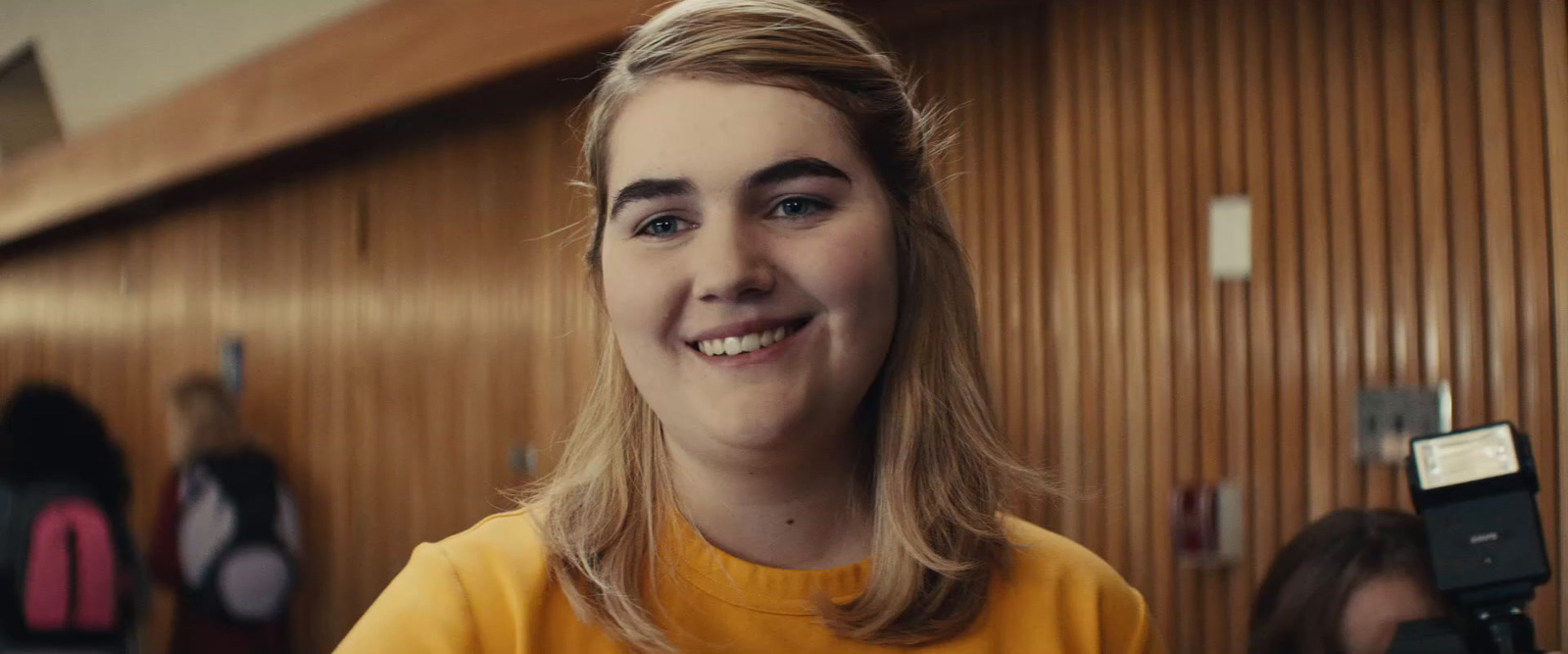 a woman in a yellow shirt holding a cell phone