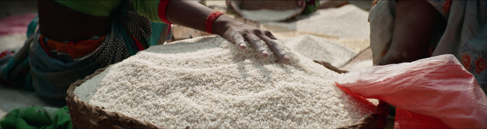 a woman in a green shirt is cutting a piece of bread