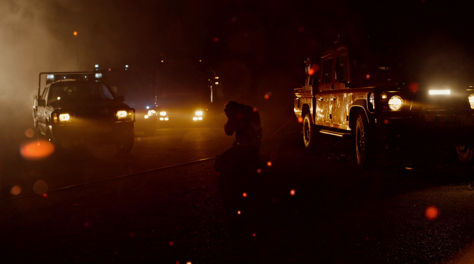 a couple of trucks driving down a street at night