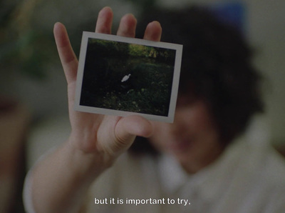 a person holding up a polaroid with a picture of a bird on it