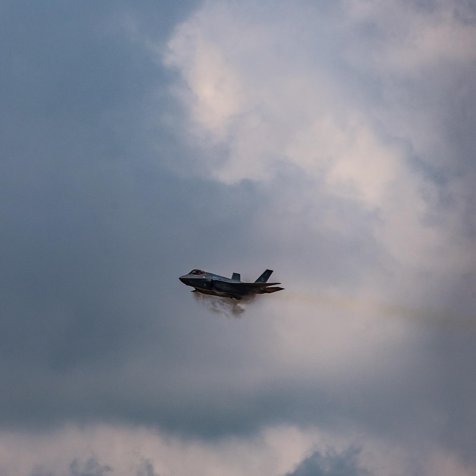 a fighter jet flying through a cloudy sky