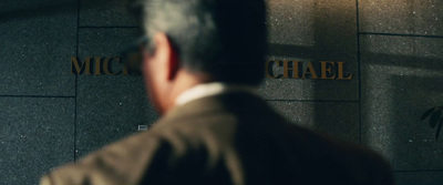 a man in a suit standing in front of a wall