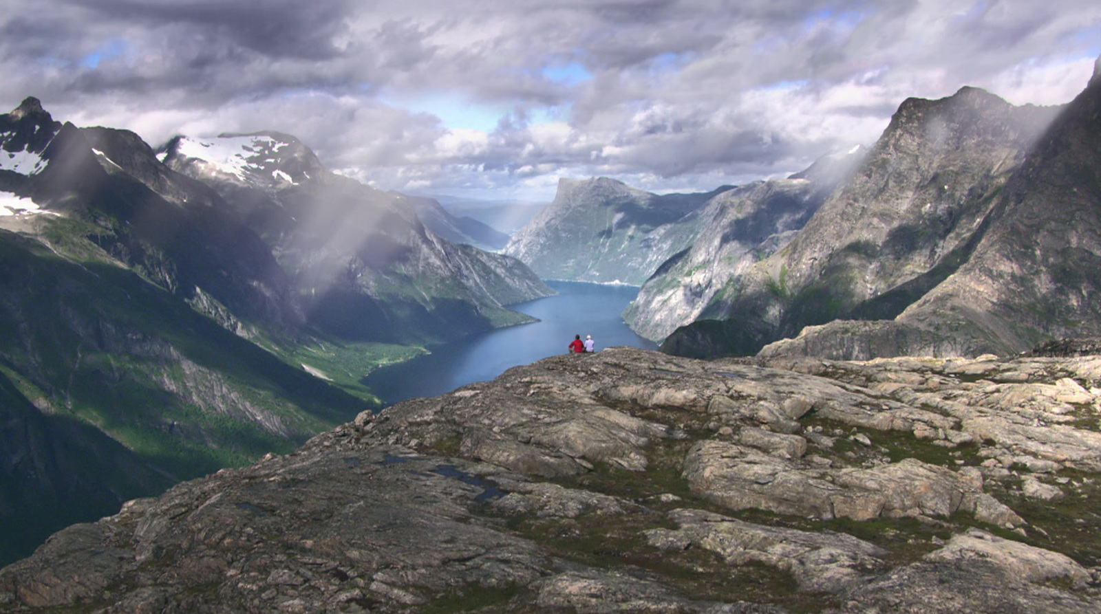 a person standing on top of a mountain overlooking a lake