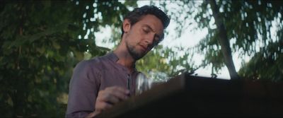 a man standing in front of a tree looking at a piece of paper