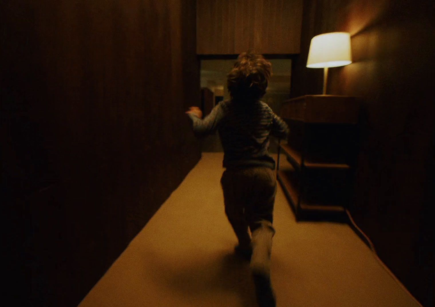 a little boy running down a hallway in a house