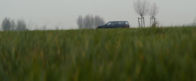 a truck is driving through a field of tall grass