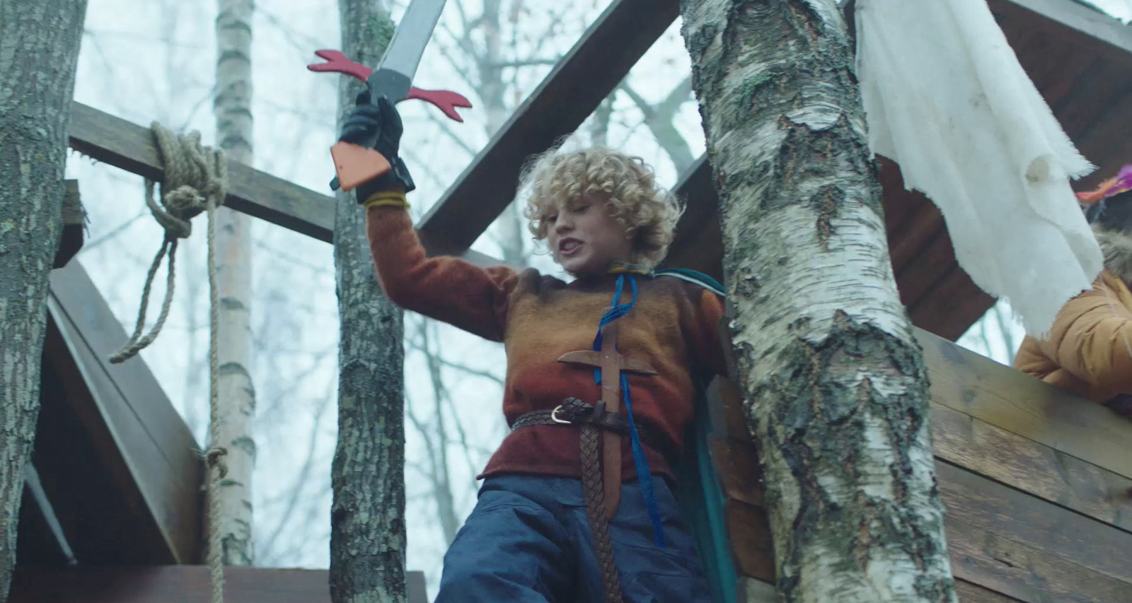 a young boy holding a pair of scissors up to a tree