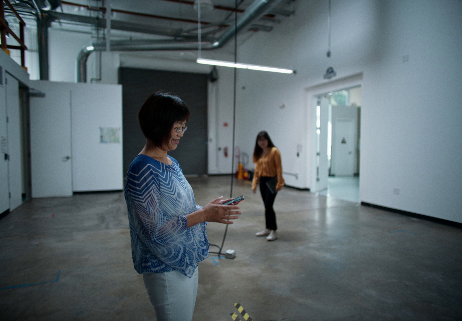 a woman standing in a room holding a cell phone