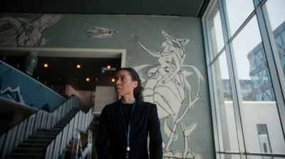 a woman standing in front of a wall with a mural on it